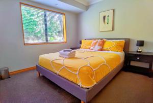 a bedroom with a bed with orange pillows and a window at Tranquil Stream Villa in Rotorua