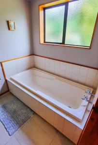 a bath tub in a bathroom with a window at Tranquil Stream Villa in Rotorua