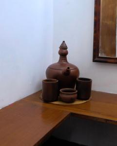 a brown pot sitting on a table with three cups at Jogja ethnic house in Yogyakarta