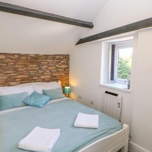 a bedroom with a blue bed with a stone wall at Pear Tree Cottage in Bishop Auckland