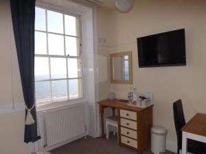a room with a desk and a television and a window at The Edenhurst Guesthouse in Weymouth