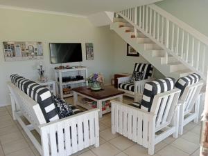 a living room with white chairs and a staircase at Sea Breeze in Stilbaai