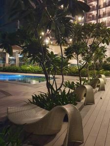una fila de bancos con árboles y una piscina en Brand new cozy condo w/ a perfect city lights view, en Manila