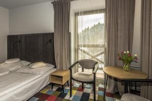 een slaapkamer met een bed, een stoel en een raam bij OSW Pan Tadeusz in Krynica Zdrój