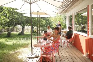 uma mulher sentada numa mesa debaixo de um guarda-chuva no alpendre em Herdade da Matinha Country House & Restaurant em Cercal do Alentejo