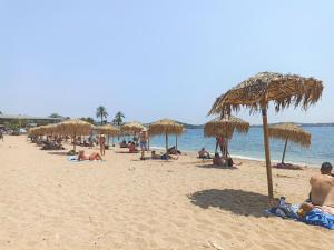 a group of people sitting on a beach with umbrellas at Galini Palace in Athens