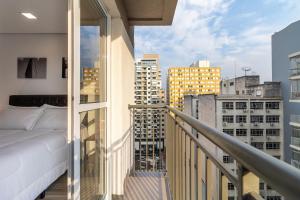 a balcony with a bed and a view of a city at Studio Bela Vista Teatro Renault in Sao Paulo