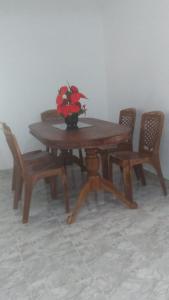 una mesa de madera con sillas y un jarrón con flores. en Cinnamon Villa Boossa, en Busse