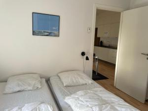 twee bedden in een witte kamer met een foto aan de muur bij Skagen Havn Lejligheder in Skagen