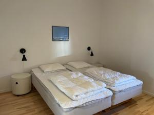 a bedroom with two beds and a tv on the wall at Plesners Havnelejligheder in Skagen