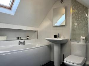 a bathroom with a sink and a tub and a toilet at West End House • Sleeps 8 in Leicester
