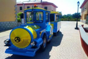 a blue and yellow train parked in a parking lot at residence afrodite in Solfara Mare