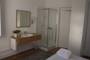 a bathroom with a sink and shower with a mirror at WW Hostel & Suites in Coimbra