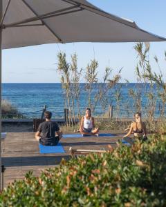 a group of people sitting on yoga mats by the ocean at Hostal Aigua Clara in Playa Migjorn