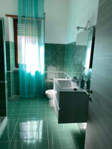 uma casa de banho verde com um lavatório e um WC em CASA GIULIA em Olbia