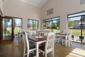 a dining room with white chairs and tables and windows at Monte Bello Estate, Cork Tree Collection in Bloemfontein