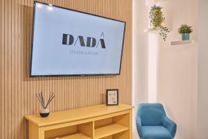 einen Flachbild-TV an einer Wand mit einem blauen Stuhl in der Unterkunft Dadá Coliving & Rooms by Serendipia Turismo in Santiago de Compostela