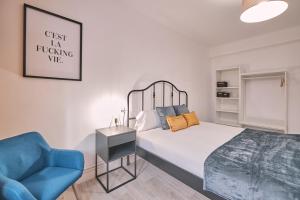 ein Schlafzimmer mit einem Bett und einem blauen Stuhl in der Unterkunft Dadá Coliving & Rooms by Serendipia Turismo in Santiago de Compostela
