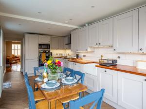 a kitchen with white cabinets and a table and chairs at Trinity Cottage in Shottery