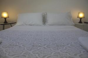 a bed with white sheets and two lamps on two tables at WW Hostel & Suites in Coimbra