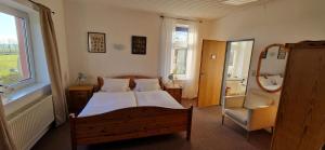 a bedroom with a bed and a chair and a window at Pension Altes Zollhaus in Norden