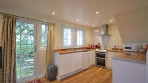 a kitchen with white cabinets and a large window at 36 Tudor Court, Tolroy Manor in Hayle