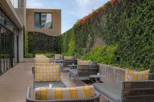 a patio with chairs and tables and a green wall at Hyatt Centric Las Condes Santiago in Santiago