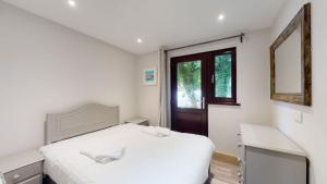 a white bedroom with a bed and a window at 48 Trevithick Court, Tolroy Manor in Hayle