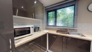 a small kitchen with a sink and a microwave at 48 Trevithick Court, Tolroy Manor in Hayle