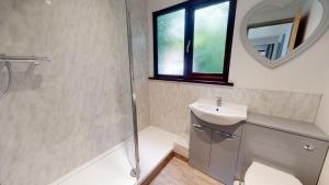 a bathroom with a shower and a sink and a mirror at 48 Trevithick Court, Tolroy Manor in Hayle +9 photos
