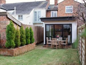 a patio with a table and chairs in a yard at Trinity Cottage in Shottery