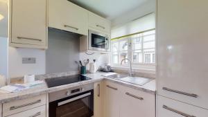 a kitchen with white cabinets and a sink and a window at 28 Tudor Court, Tolroy Manor in Hayle