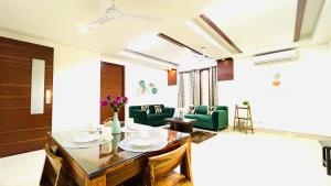 Olive Service Apartments - Green Park في نيودلهي: غرفة معيشة مع طاولة وكراسي خضراء