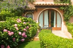 un jardín con flores y un banco frente a una casa en AFFITTACAMERE SA BRATZA VACANZE en Domus de Maria