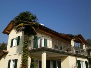 a building with a palm tree in front of it at Casamanax in Maccagno Inferiore