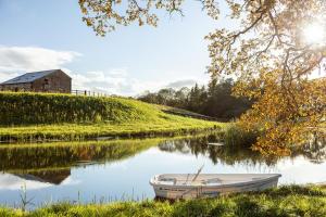 ein Boot auf einem Fluss mit einer Scheune im Hintergrund in der Unterkunft The Casterton Grange Estate in Kirkby Lonsdale