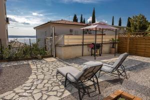 een patio met 2 stoelen en een parasol bij Apartment Levante in Crikvenica