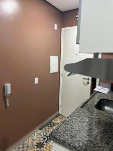 cocina con encimera, fregadero y puerta en flat reg central sp varanda e Wi-Fi grátis 500 megas, en São Paulo