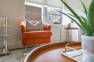 an orange chair in a living room with a window at California Building by Hosteeva in New Orleans