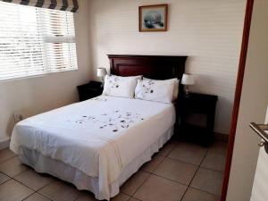 1 dormitorio con 1 cama grande con sábanas y almohadas blancas en Umkhomo Place, Mangrove Beach Estate, en Port Shepstone
