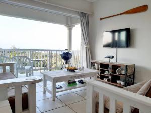 a living room with a table and a tv on the wall at Umkhomo Place, Mangrove Beach Estate in Port Shepstone