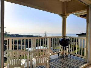 a porch with a grill and two chairs and a table at Umkhomo Place, Mangrove Beach Estate in Port Shepstone