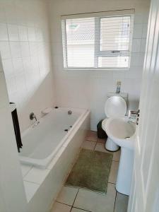 a bathroom with a tub and a toilet and a sink at Umkhomo Place, Mangrove Beach Estate in Port Shepstone