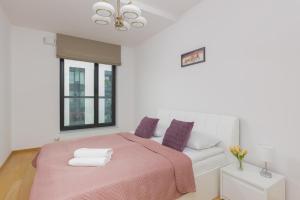 ein weißes Schlafzimmer mit einem rosa Bett und einem Fenster in der Unterkunft Dzielna Apartment Warsaw Wola by Renters in Warschau