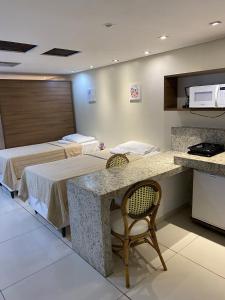 若昂佩索阿的住宿－Imperial Flat Tambaú - João Pessoa，客房设有两张床、一张桌子和一台微波炉。