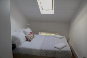 a bedroom with a bed with white sheets and a window at WW Hostel & Suites in Coimbra