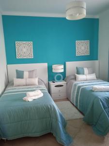 two beds in a room with blue walls at Orlanda Veríssimo in Nazaré