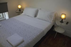 a bedroom with a white bed with two tables and two lamps at WW Hostel & Suites in Coimbra