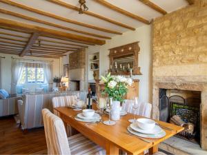 comedor con mesa y chimenea en Swift Cottage en Blockley
