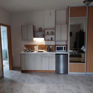 cocina con armarios blancos, fregadero y microondas en Miško apartamentai 50m2, en Juodkrantė